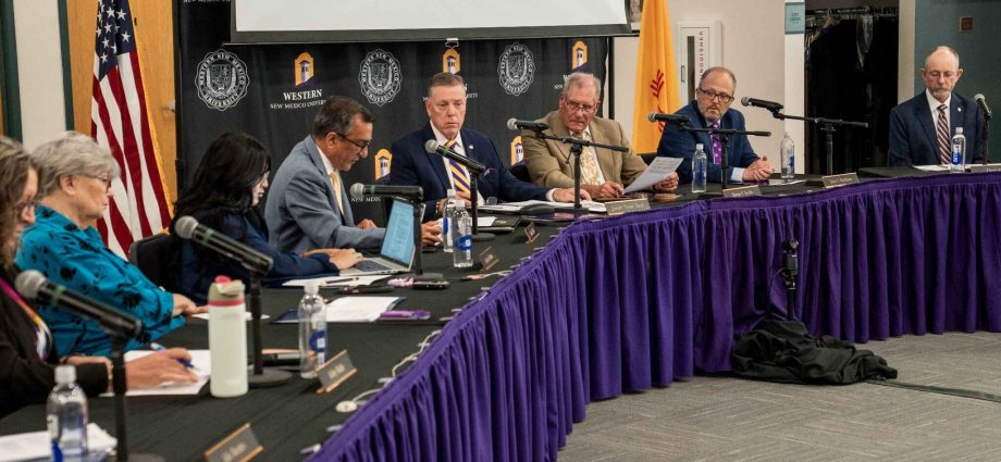 Western New Mexico University regents and administrators seated at tables with microphones during a board meeting.