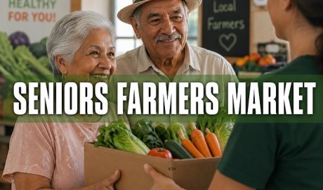 Older couple receiving a box filled with fresh vegetables at a farmers market.
