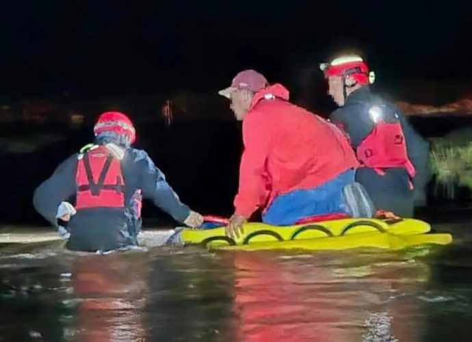 U.S. Border Patrol rescue personnel wade through floodwater during a nighttime rescue in the Deming area.