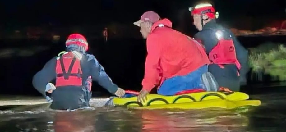 U.S. Border Patrol rescue personnel wade through floodwater during a nighttime rescue in the Deming area.