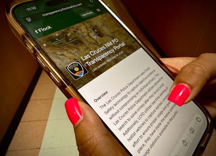 A person holds a phone displaying a Las Cruces information page.
